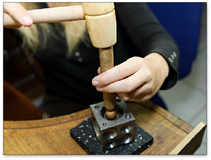 Emboutissage de métal dans un dé avec un maillet et bouterolle en buis - formation bijouterie - joaillerie.